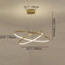 Gold metal ring chandelier with LED lighting suspended from ceiling against neutral background.