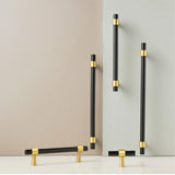 "Set of black and gold brass pull bars with cylindrical design and subtle accents, arranged on a grey and white surface."