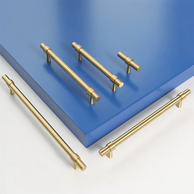 "Set of gold brass pull bars with cylindrical design and subtle accents, arranged on a blue and white surface."