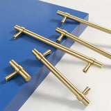"Gold brass pull bars with cylindrical design and subtle accents, arranged on a blue and white surface."