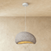 Three gray concrete dome pendant lights with warm interiors suspended above a cream sectional sofa in modern living room sett