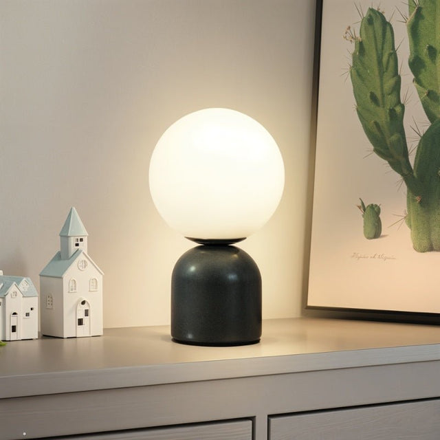 Sibwa Table Lamp with black base and glowing globe on a dresser, perfect for modern bedroom or hallway lighting decor.