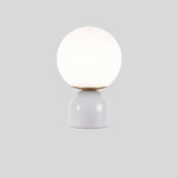 Sibwa Table Lamp with glossy white base and glowing globe, suitable for contemporary bedroom or living room lighting.