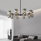 "Black iron Silvine chandelier with smoked glass spherical shades hanging above a living room with a grey sofa and modern décor."