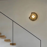 "Modern wall lamp with a fluid, grey glass shade and iron base illuminating a contemporary hallway with a staircase."