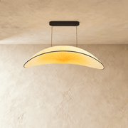 Curved cream pendant light with natural wood finish above modern gray sofa in minimalist studio setting.