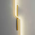 Gold geometric wall lamp with linear design mounted on white wall, emitting warm light.