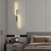 Slant wall lamp in warm brass finish mounted above bedside table in modern bedroom.
