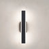 Black vertical wall lamp with integrated side lighting elements mounted on a white wall.