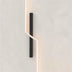 Black and white modern wall lamp mounted on a minimalist white wall with subtle shadow accent.