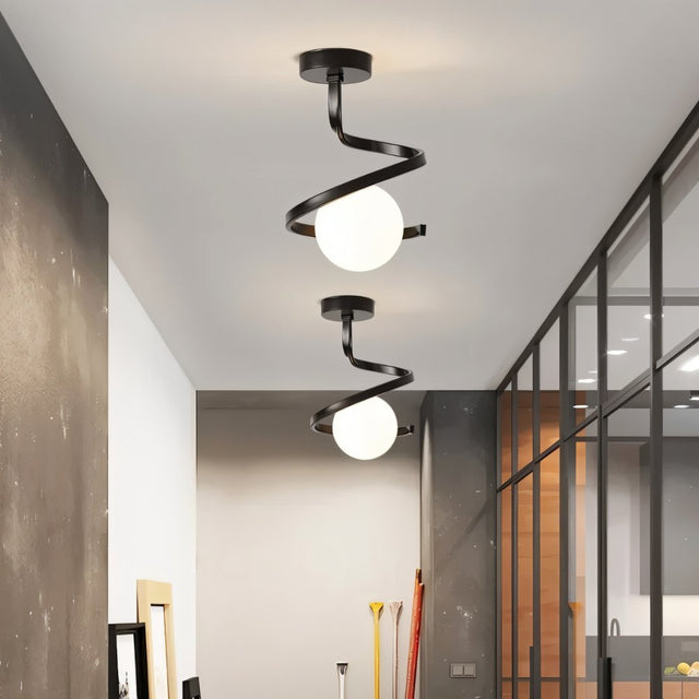 "Two modern black ceiling lights with spiral frames and frosted glass globes in a long hallway with gray walls and a glass partition."