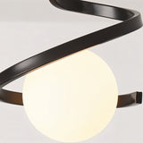"A close-up view of the Slym ceiling light showing the black spiral frame and lit frosted glass globe."