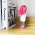 Bright pink and white vinyl figurine with metallic silver legs and oversized balloon-like head displayed on wooden shelf.