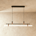 Linear pendant light with white frosted glass and wood accents, suspended against marble and wood kitchen cabinetry, studio w