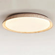"Close-up of a minimalist ceiling light with a soft yellow travertine ring and acrylic diffuser, emitting a soft, even glow."