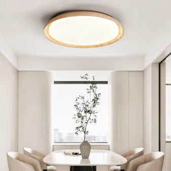 "Minimalist ceiling light with a soft yellow travertine ring and acrylic diffuser, illuminating a contemporary dining room with a calming ambiance."