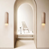 "Solon travertine wall lamp casting ambient light, enhancing a minimalist space with natural textures and subtle variations in the travertine surface."