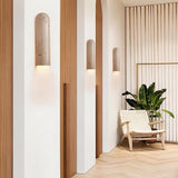 "Solon travertine wall lamps illuminating a stylish living room with natural textures, creating a warm and inviting ambiance."