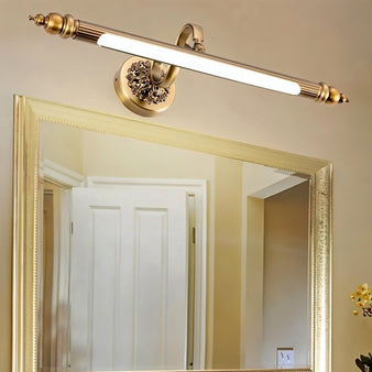 "Close-up of a retro copper wall lamp with intricate detailing and an elegant rod-shaped light fixture, mounted above a bathroom mirror."