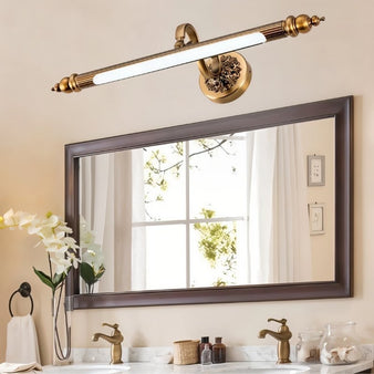 "A retro copper wall lamp with intricate detailing and an elegant rod-shaped light fixture, mounted above a rectangular bathroom mirror with double sinks."