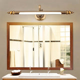 "A retro copper wall lamp with intricate detailing and an elegant rod-shaped light fixture, mounted above a rectangular bathroom mirror with a white countertop and double sinks."