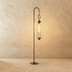 Tall cylindrical wind chime with hanging tubular chime and curved hook top on round base, shown on white background.