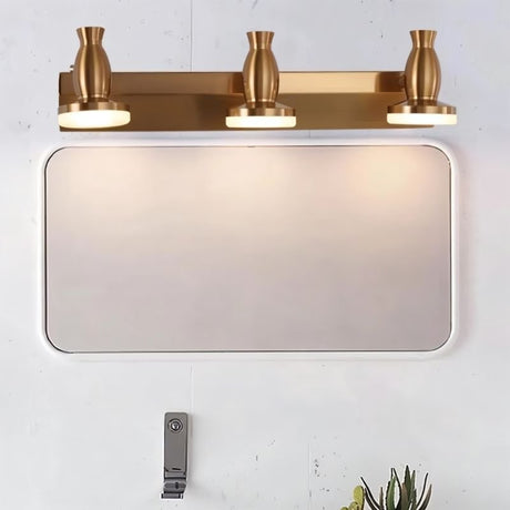 "A modern, 3-head vanity light in a brushed gold finish mounted above a bathroom mirror."