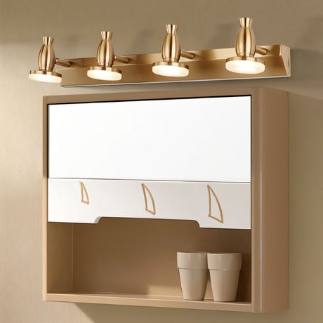 "A modern, 4-head vanity light in a brushed gold finish mounted above a bathroom cabinet with a mirror."