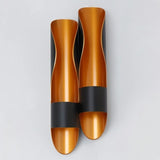 "Modern wall lamp with a dual-tube, flame-inspired design and a contrasting black and gold finish."