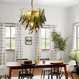 "Murano glass chandelier with green and red accents, hanging above a wooden dining table in a bright dining room."