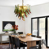  "Murano glass chandelier with green and red accents, hanging above a wooden dining table in a modern dining room with artwork."