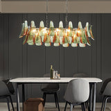 "Murano glass chandelier with green and red accents over a dining table in a modern dining room."