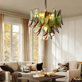 "Murano glass chandelier with green and red accents, hanging in a living room with a sofa and large windows."