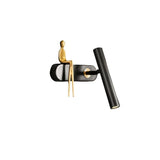 "A black and gold bedside reading lamp with a figurine, isolated on a white background."