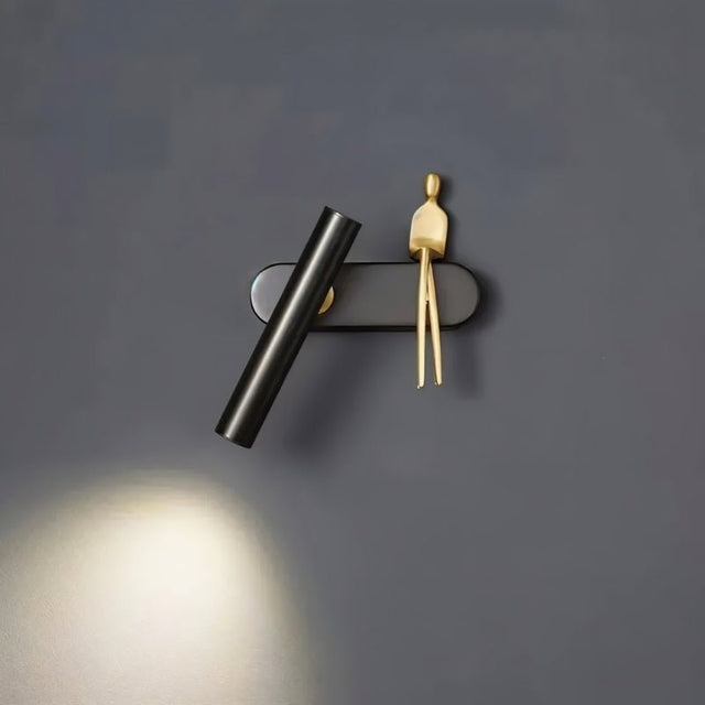 "A black and gold bedside reading lamp on a dark grey wall."