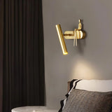 "A gold bedside reading lamp with a figurine on a wall above a bed."