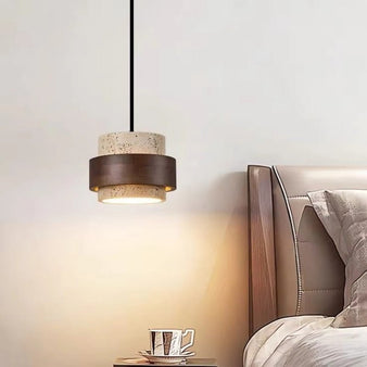 "Modern stone and wood cylindrical pendant light hanging in a bedroom, providing soft illumination."