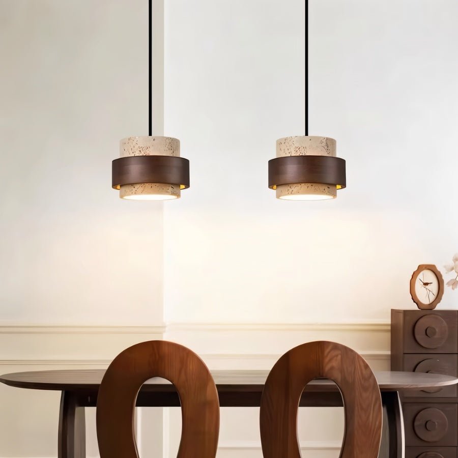 "Pair of modern stone and wood cylindrical pendant lights hanging over a dining table."