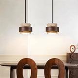 "Pair of modern stone and wood cylindrical pendant lights hanging over a dining table."