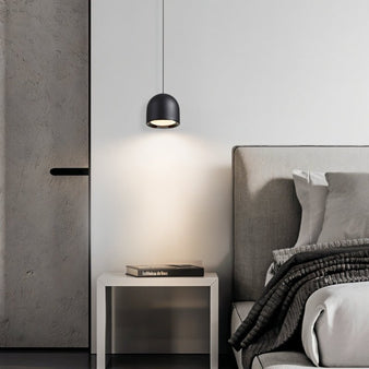 Black Sterna Pendant Light illuminating a bedside table in a contemporary bedroom, showcasing its sleek and modern design.