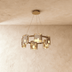 Modern brass and glass pendant light fixture with multiple cylinders hanging above marble dining table in contemporary interi