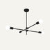 Black metal sunburst chandelier with six arms and white globe lights against a neutral background.