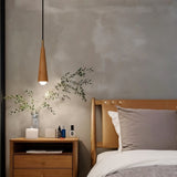 "A wooden pendant light with a copper accent illuminates a cozy bedroom setting."