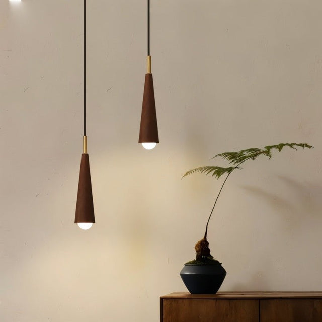 "Pair of rustic pendant lights with conical wooden shades and copper detailing hang in a warm, inviting space."
