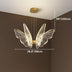 Brass butterfly-shaped chandelier with LED acrylic wings hanging in a brown room interior.