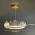 Modern brass pendant chandelier with petal-shaped acrylic shades, suspended against a gray wall.