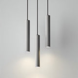 "Three gray cylindrical pendant lights hanging from black cords against a light gray background."