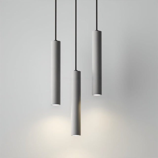 "Three gray cylindrical pendant lights hanging from black cords against a light gray background."