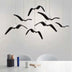 Black curved pendant lights with chrome accents suspended above a white desk in a modern office setting.