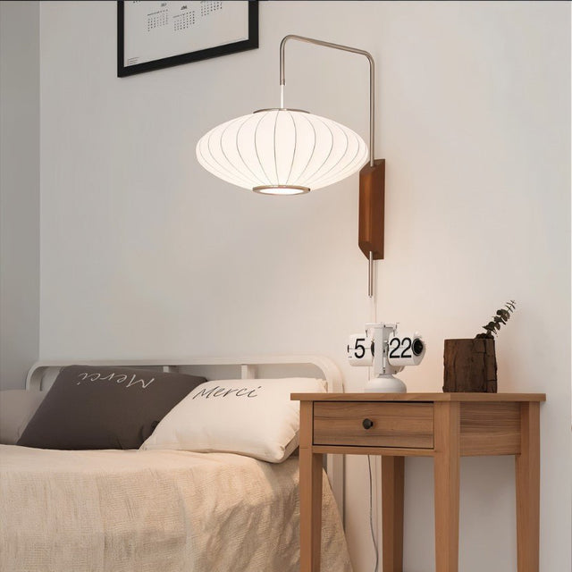 "A minimalist bedroom featuring a modern wall lamp with a silk shade, providing soft, ambient light above a bedside table."